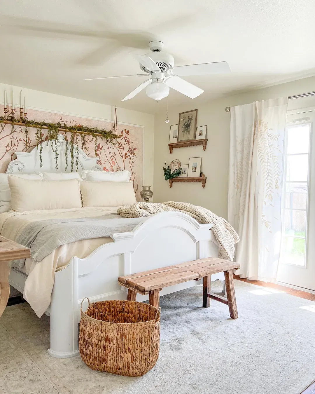 Bedroom with white bed, floral wallpaper, wood bench, and woven basket.