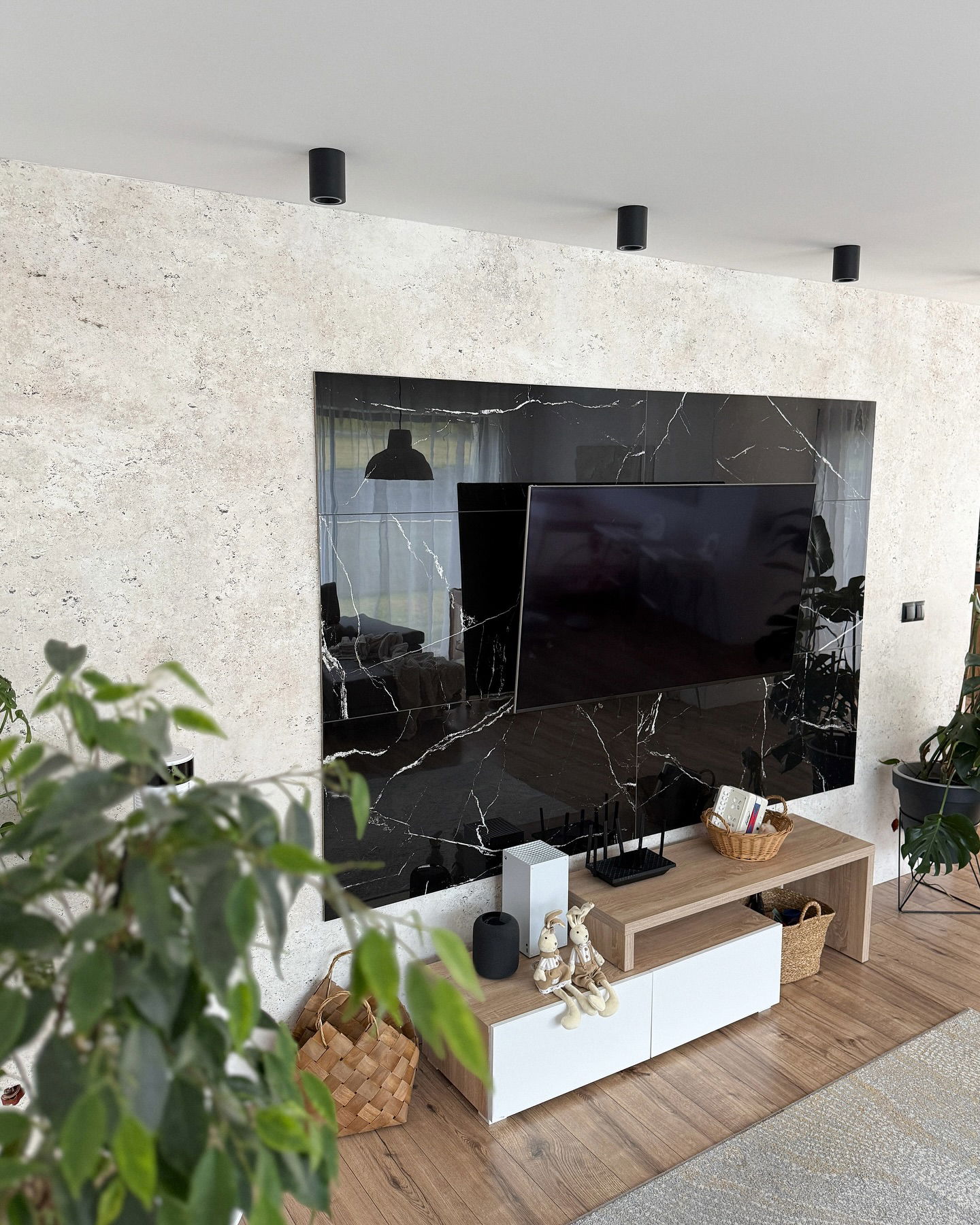 Living room with black marble accent wall, TV, and light wood media console.