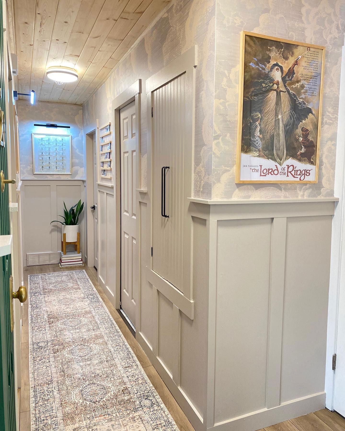 Hallway with wood ceiling, patterned wallpaper, and "Lord of the Rings" poster.