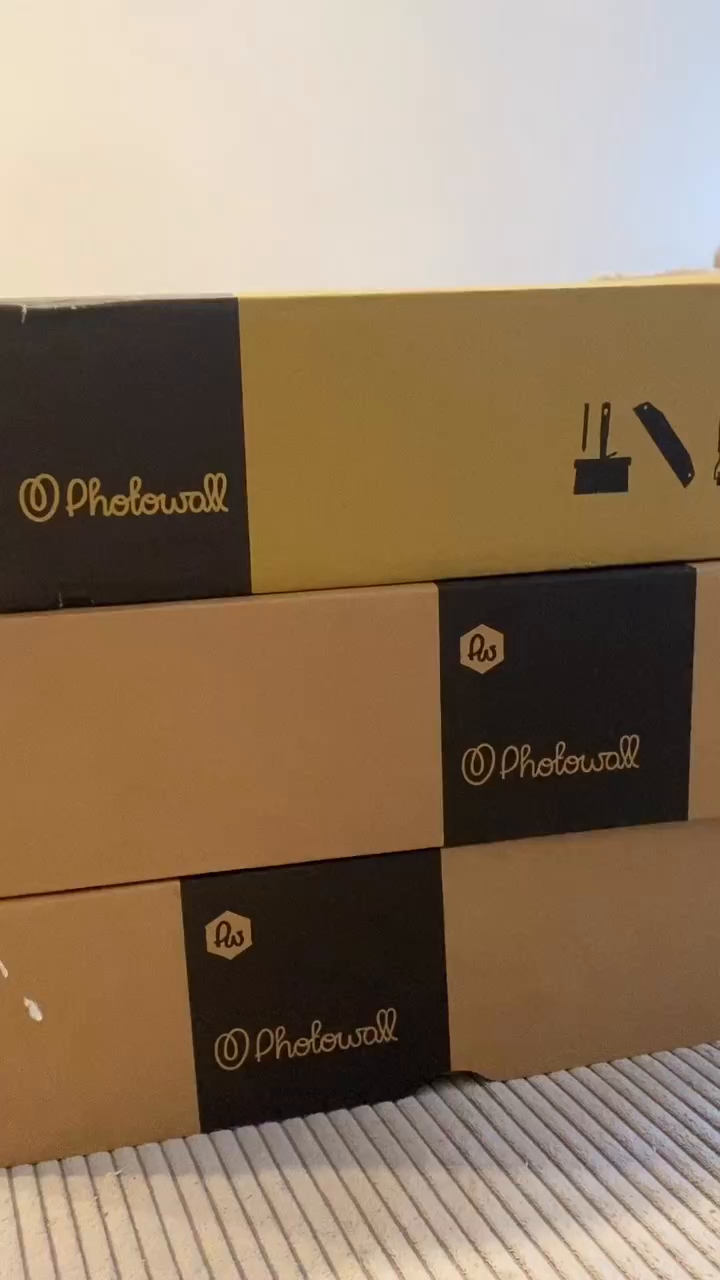 Three stacked Photowall boxes in black and tan.