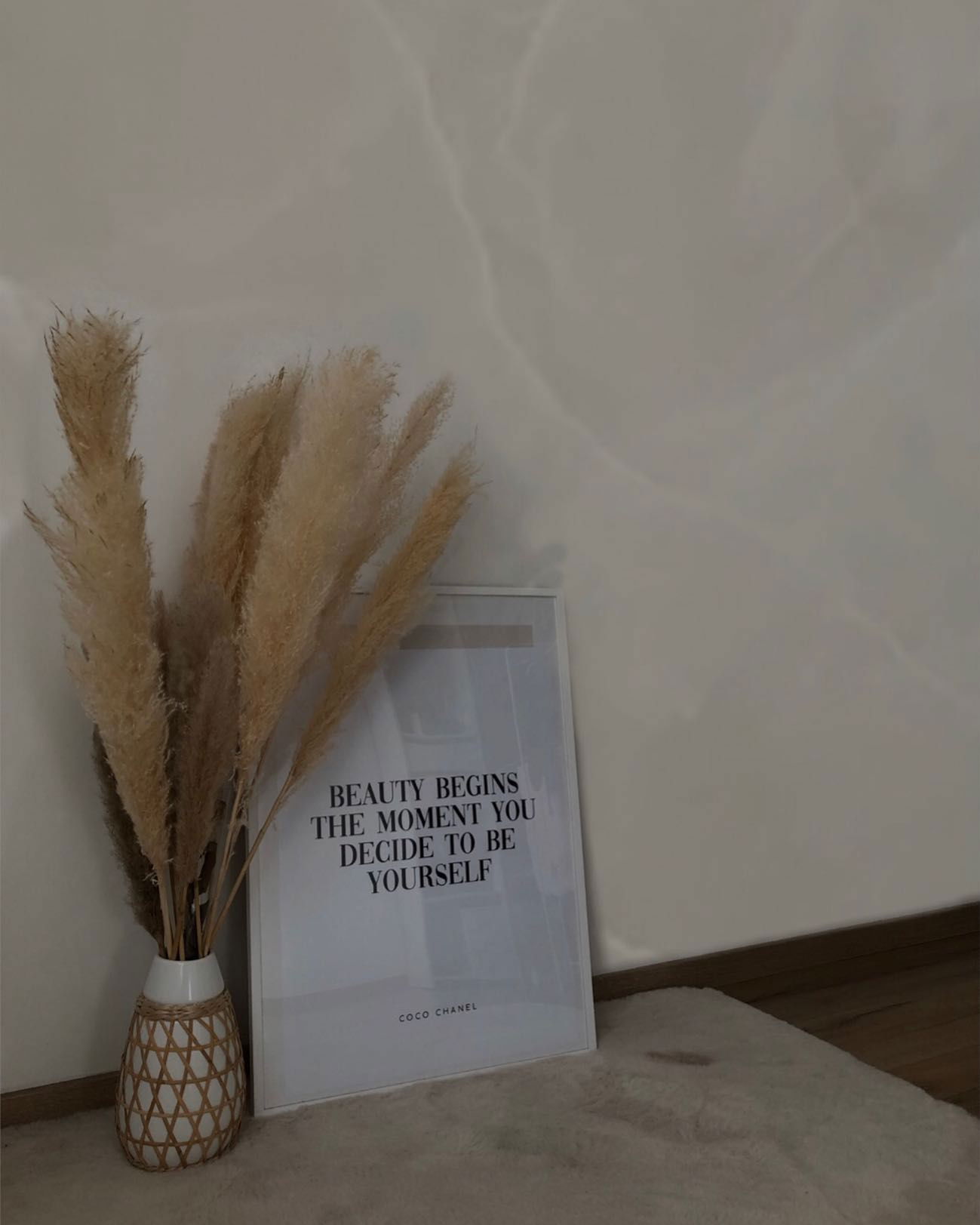 Interior decor with pampas grass in a woven vase and a Coco Chanel quote print.