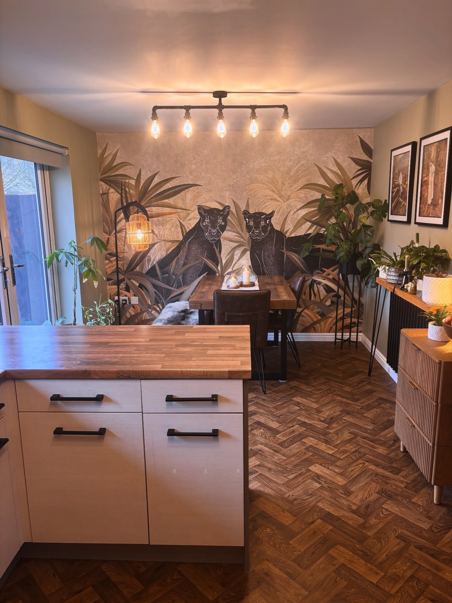 Modern dining area with a jungle mural featuring two black panthers and lush foliage.