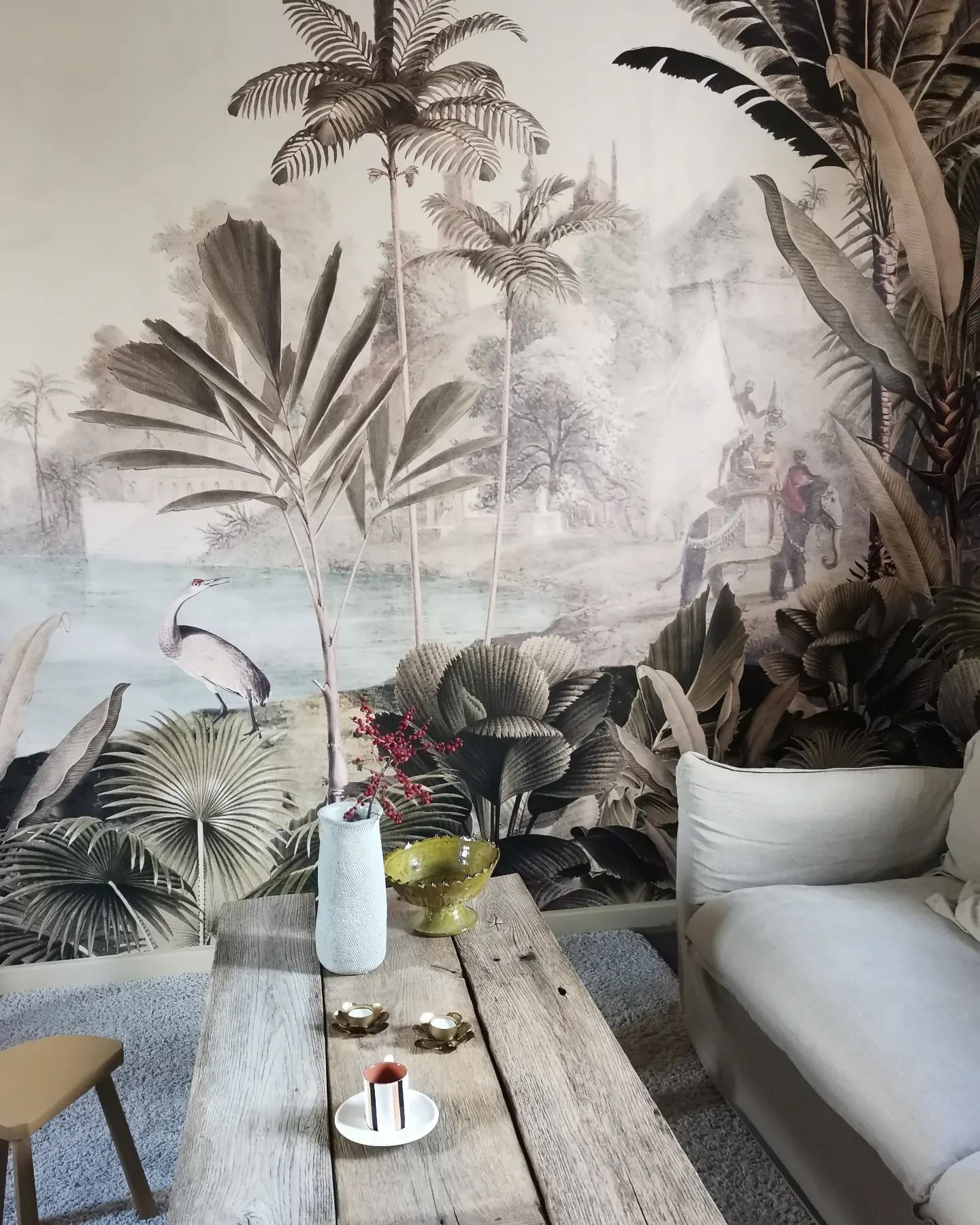 Living room with tropical mural, rustic wood table, and white sofa.