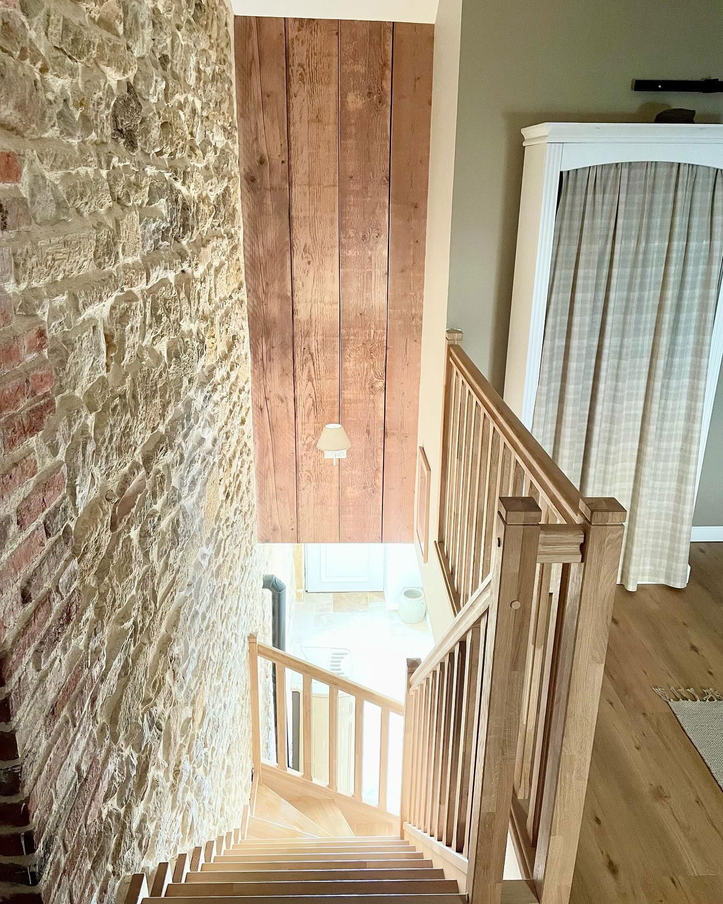 Interior view of wooden stairs with stone and wood paneled walls.