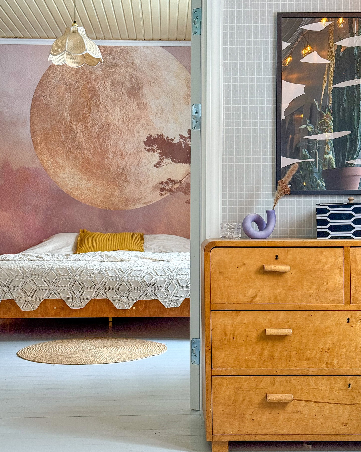 Schlafzimmer mit großer Mond-Wandmalerei und moderner Kommode mit Kunstwerk.