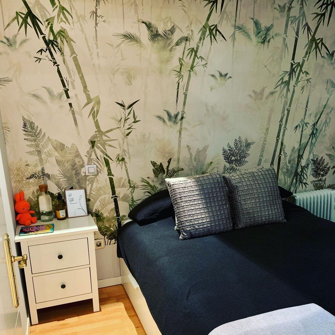 Bedroom with bamboo wallpaper, black bedding, and white nightstand.