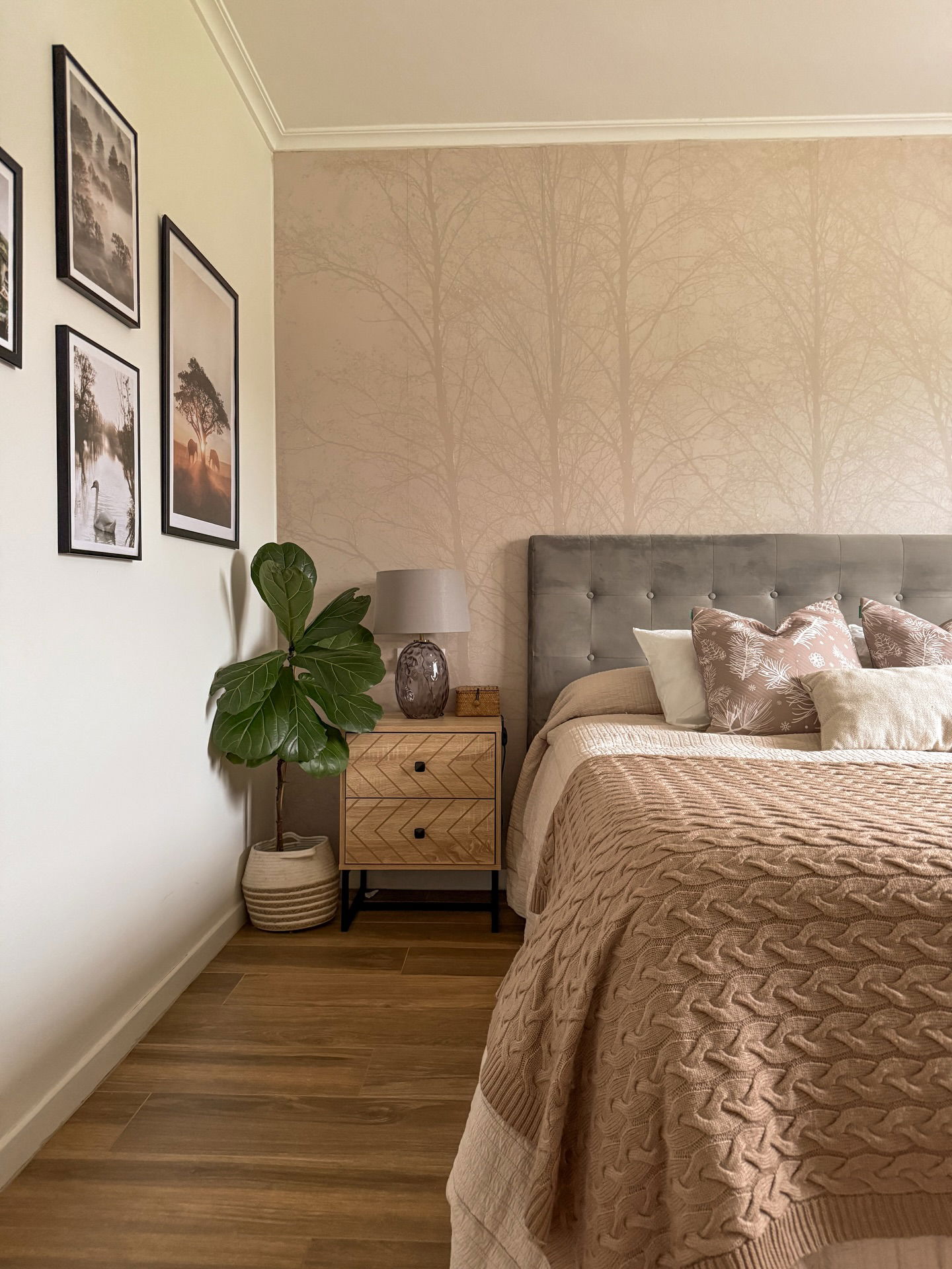 Gemütliches Schlafzimmer mit einem grauen, gepolsterten Kopfteil, flauschiger Bettwäsche und einer strukturierten Decke.
