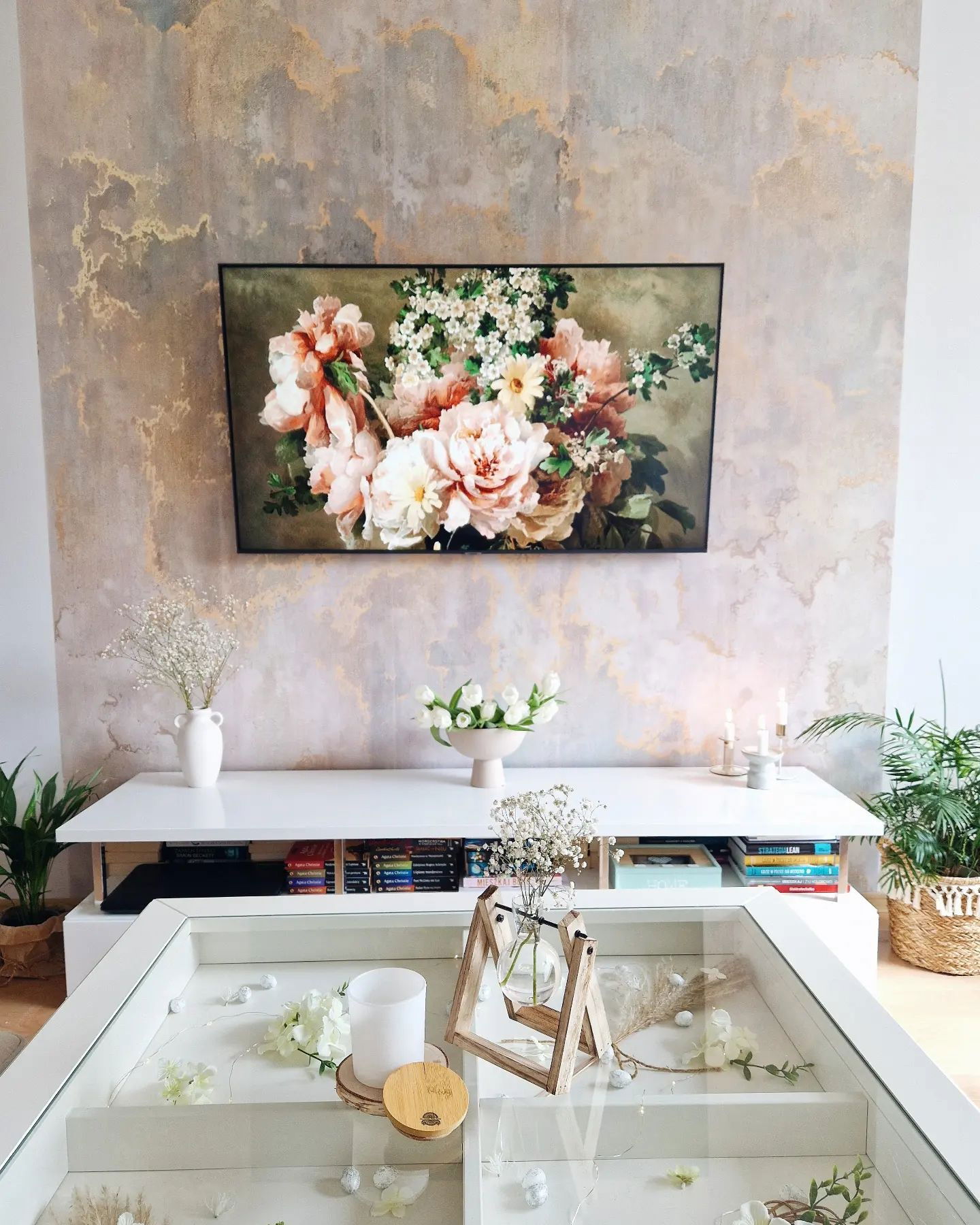 Living room with floral art above white console table and glass-topped coffee table.