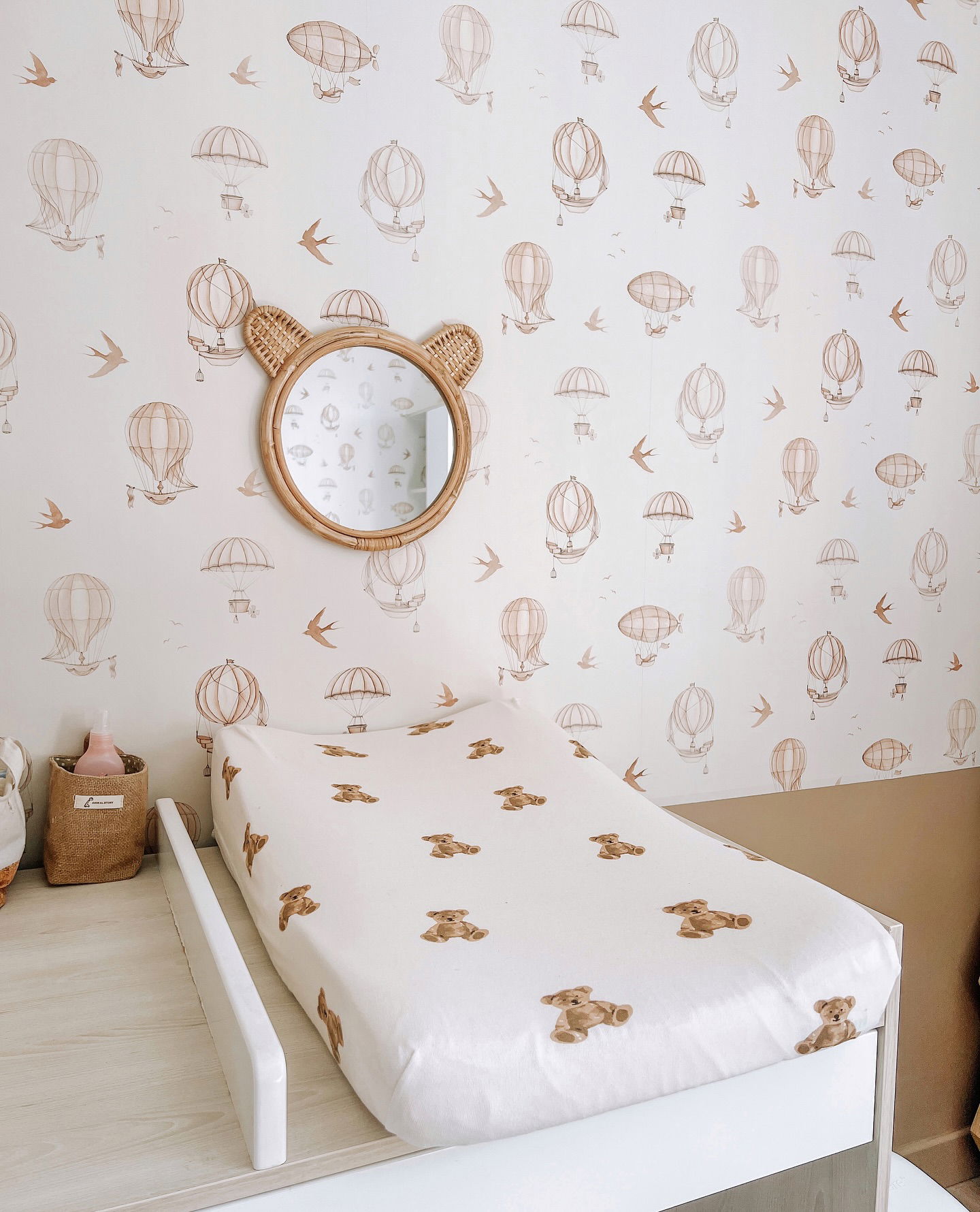Chambre de bébé avec table à langer ourson, papier peint montgolfière et miroir en forme d'ours.