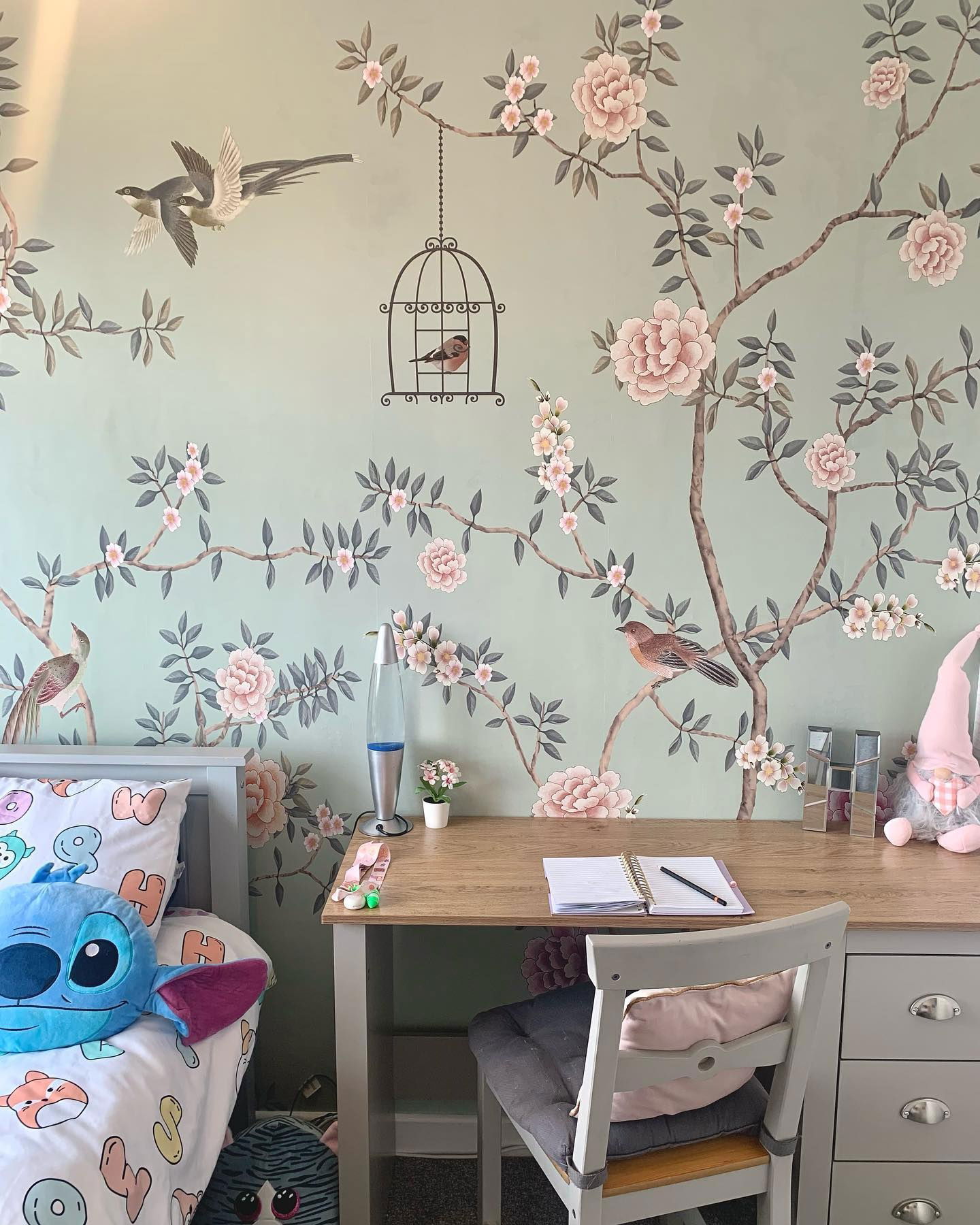Child's room with floral wallpaper, desk, and bed. A Stitch plush sits on the bed.