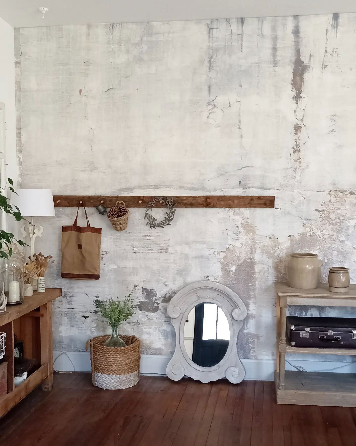 Eclectisch interieur met verweerde muur, houten meubels en decoratieve items.