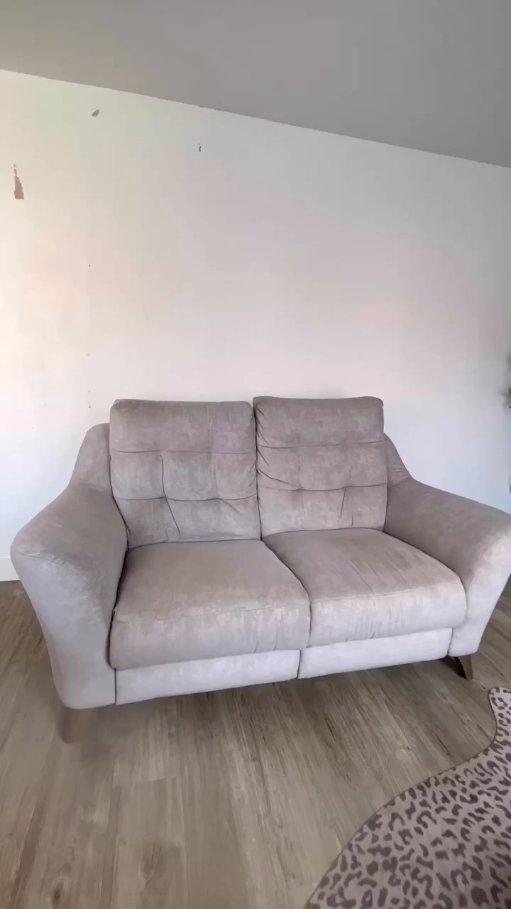 A light gray, two-cushion sofa with tufted back cushions.