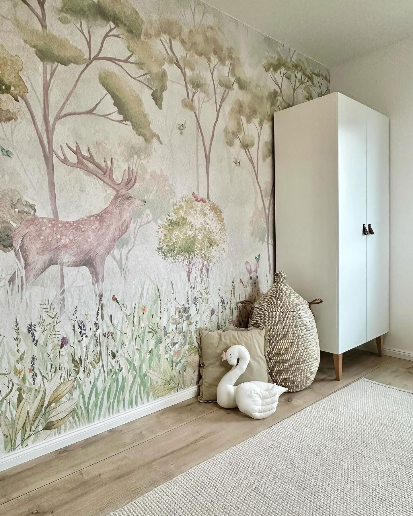 Nursery with forest mural, white wardrobe, and swan plush.