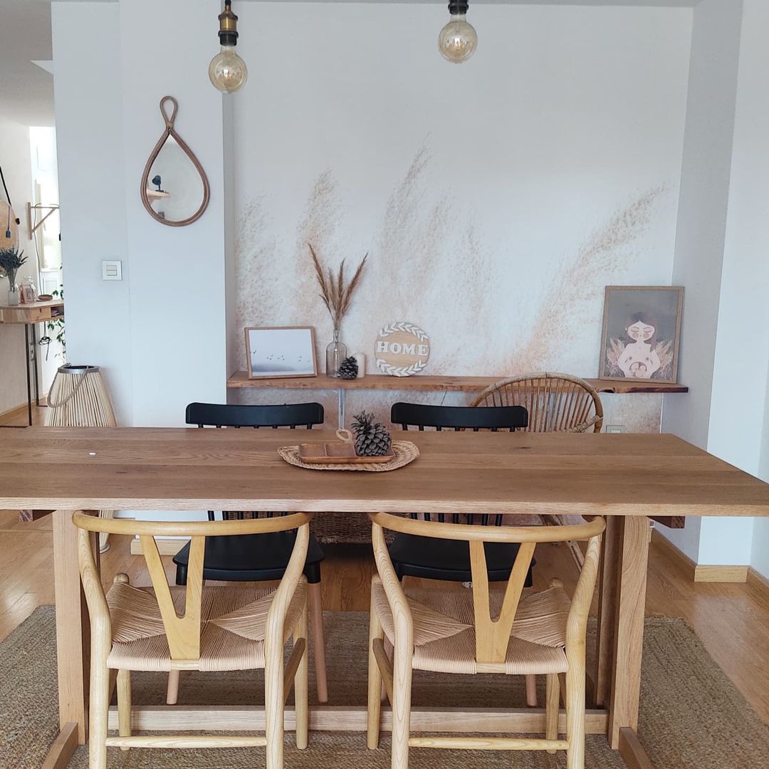 Comedor luminoso con mesa de madera, sillas de mimbre y arte decorativo en la pared.