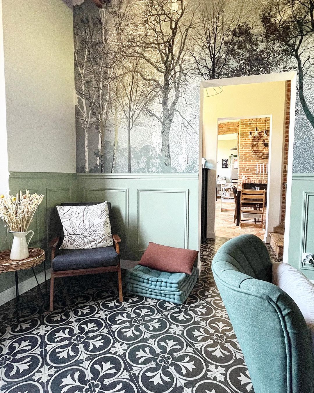 Living room with black and white patterned tile, green wainscoting, and a birch tree mural.