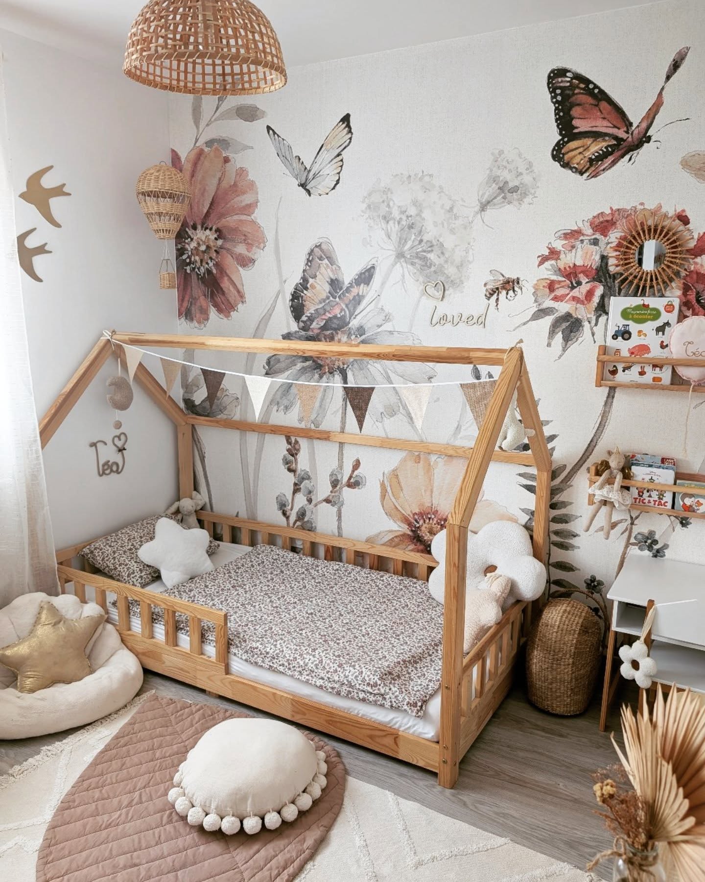 Kinderzimmer mit Holzbettgestell in Hausform, Blumentapete und neutraler Einrichtung.