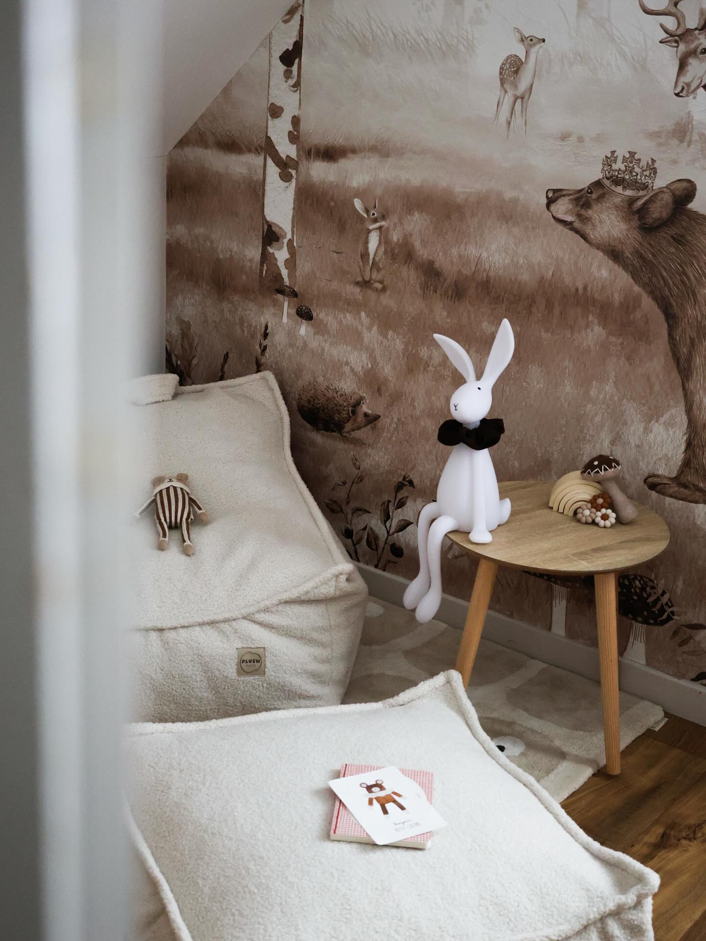 Child's room with beanbag chairs, round table, and animal-themed wallpaper.