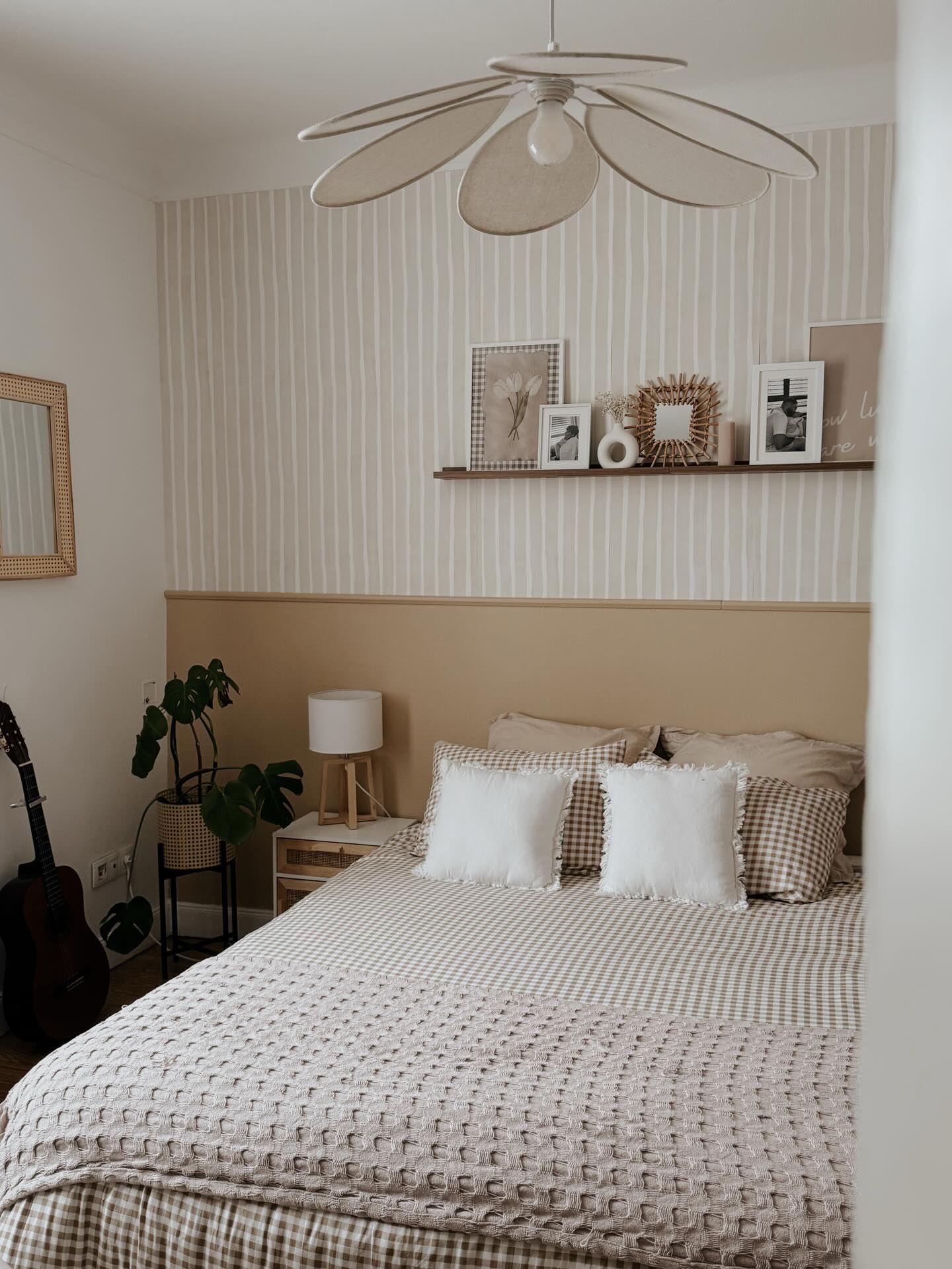Schlafzimmer mit einem Bett, einer Gitarre und gerahmten Fotos auf einem Regal.