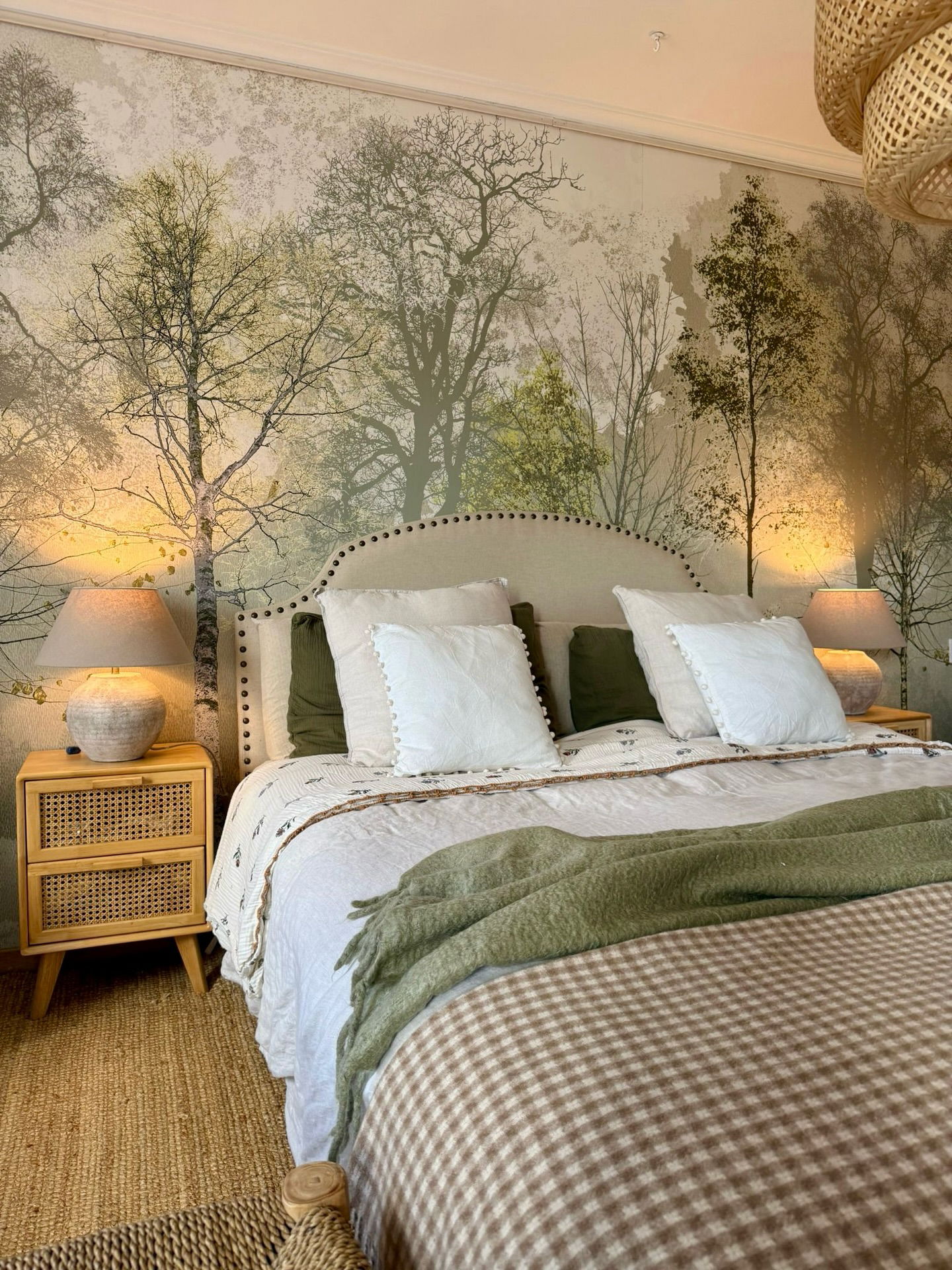 Cozy bedroom with birch tree wallpaper, upholstered headboard, and nature-themed bedding.