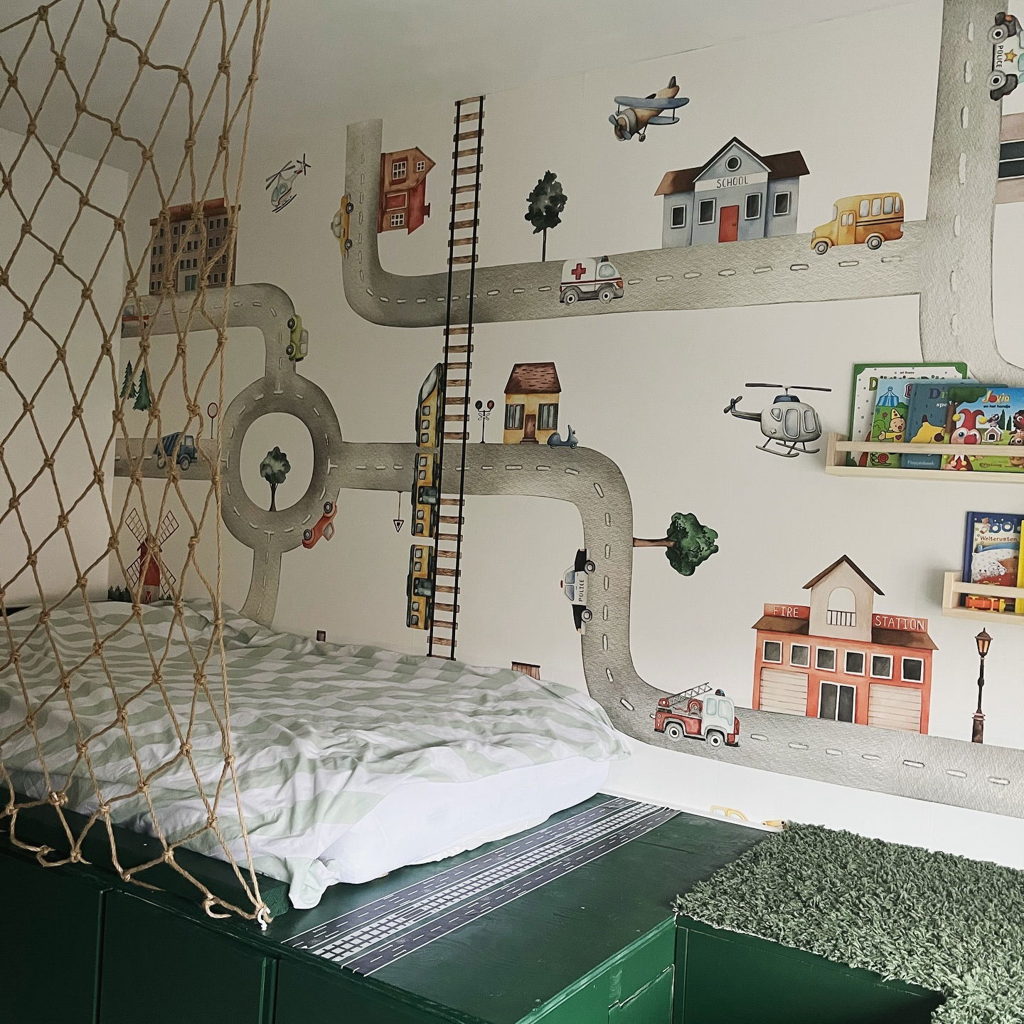 Child's bedroom with road-themed wall decals, loft bed, and rope net.