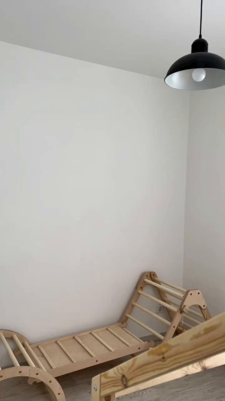 Indoor shot of a wooden climbing gym set against a white wall.