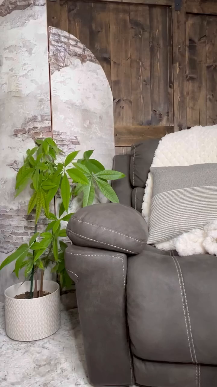 Interior with gray recliner, throw blanket, pillow, and potted money tree.
