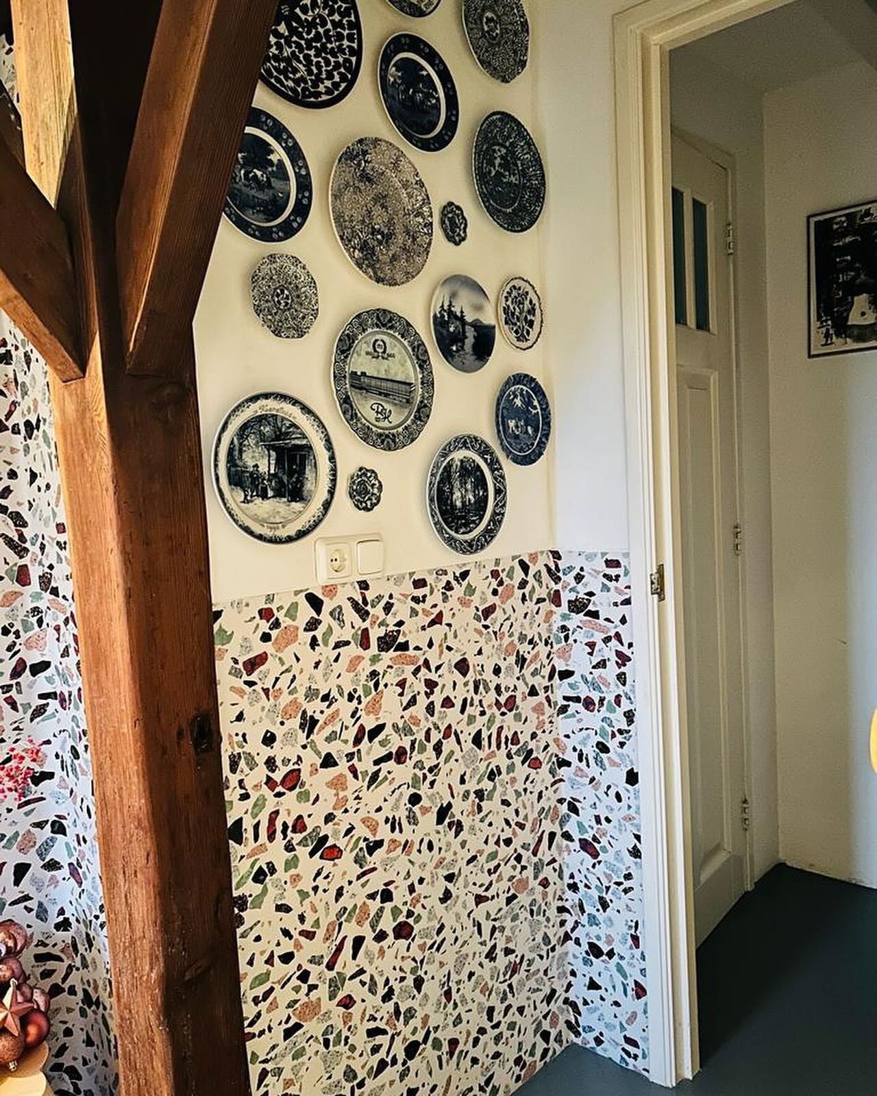Interior view of wall with decorative plates and colorful terrazzo tile.