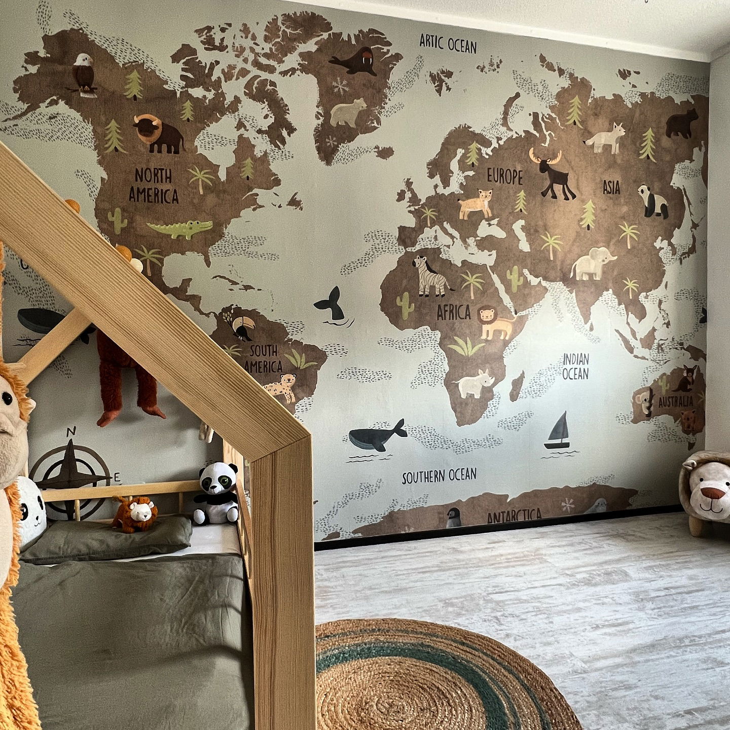 Barnerom med tapet av verdenskart med dyr, sengeramme i tre og kosedyr.