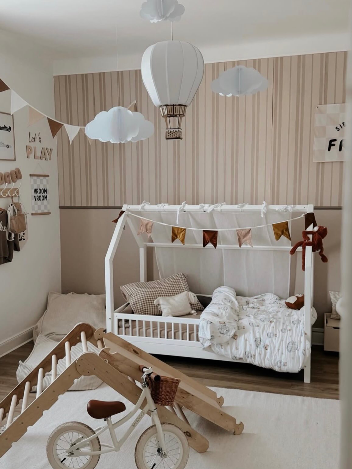 Child's room with white canopy bed, wooden climber, and bike.