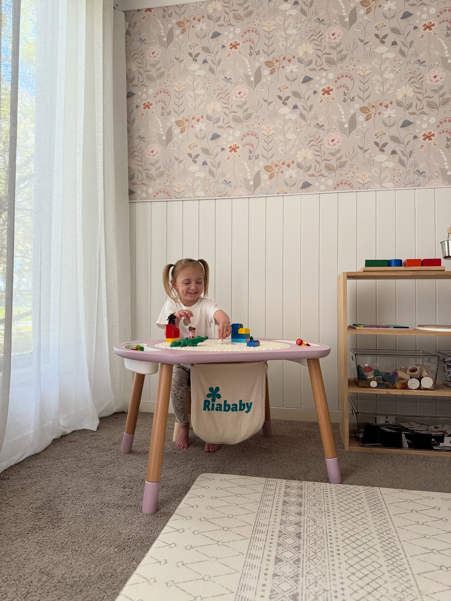 A young girl plays at the Riababy Activity Table with storage in her playroom.
