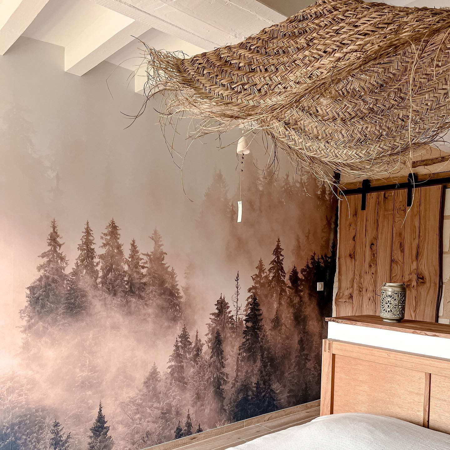 Bedroom with forest mural, woven ceiling decor, and wooden headboard.