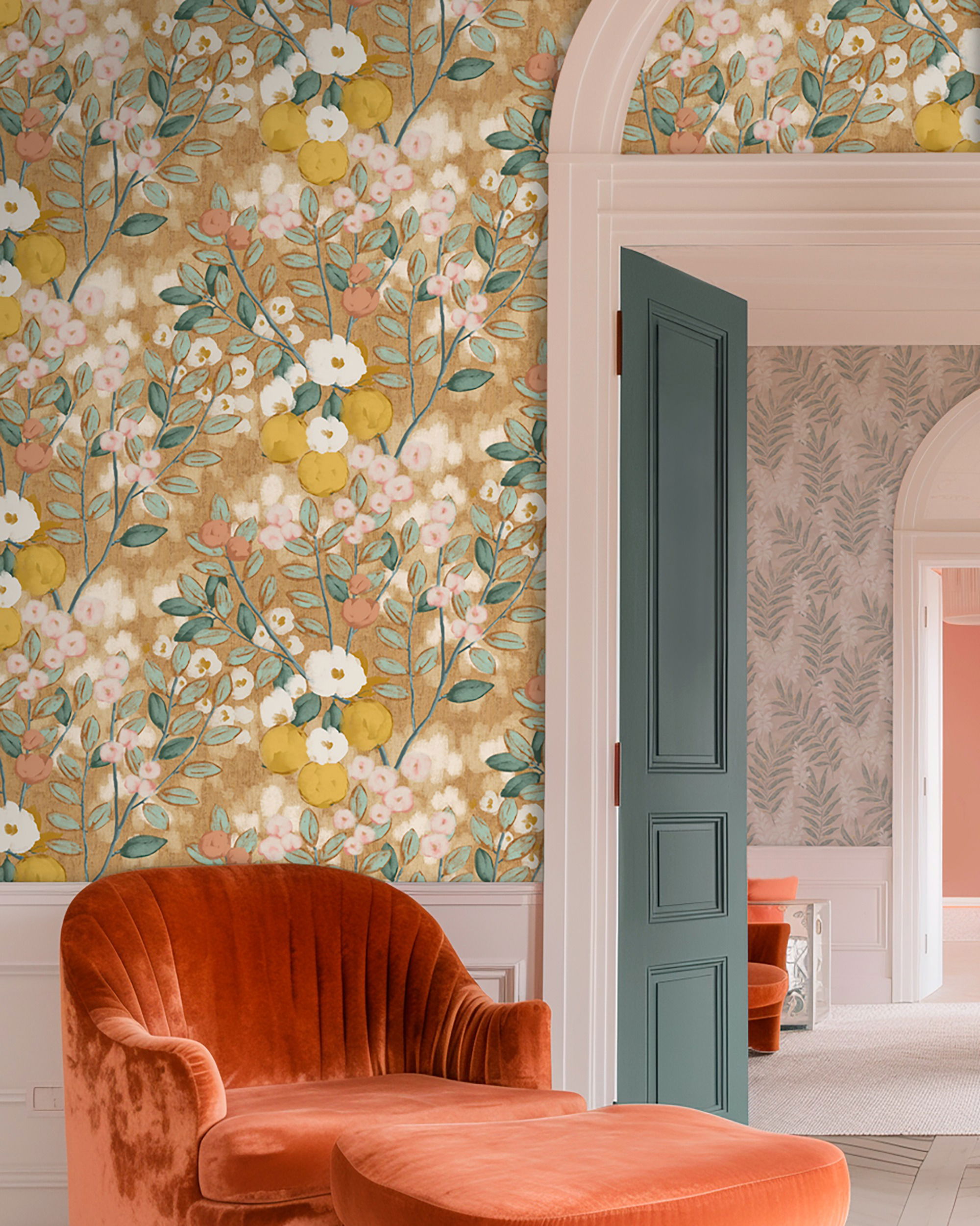 Interni con carta da parati floreale, poltrona e pouf in velluto arancione e porta verde acqua aperta.