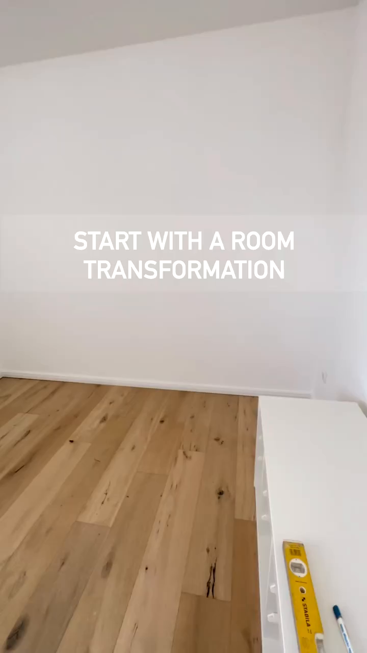 Bright room with wood floors and white walls. Text overlay reads "Start with a room transformation." A level and pen sit on a white shelf.