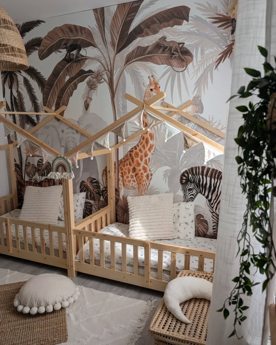 Nursery with two wooden toddler beds against a jungle-themed wallpaper.
