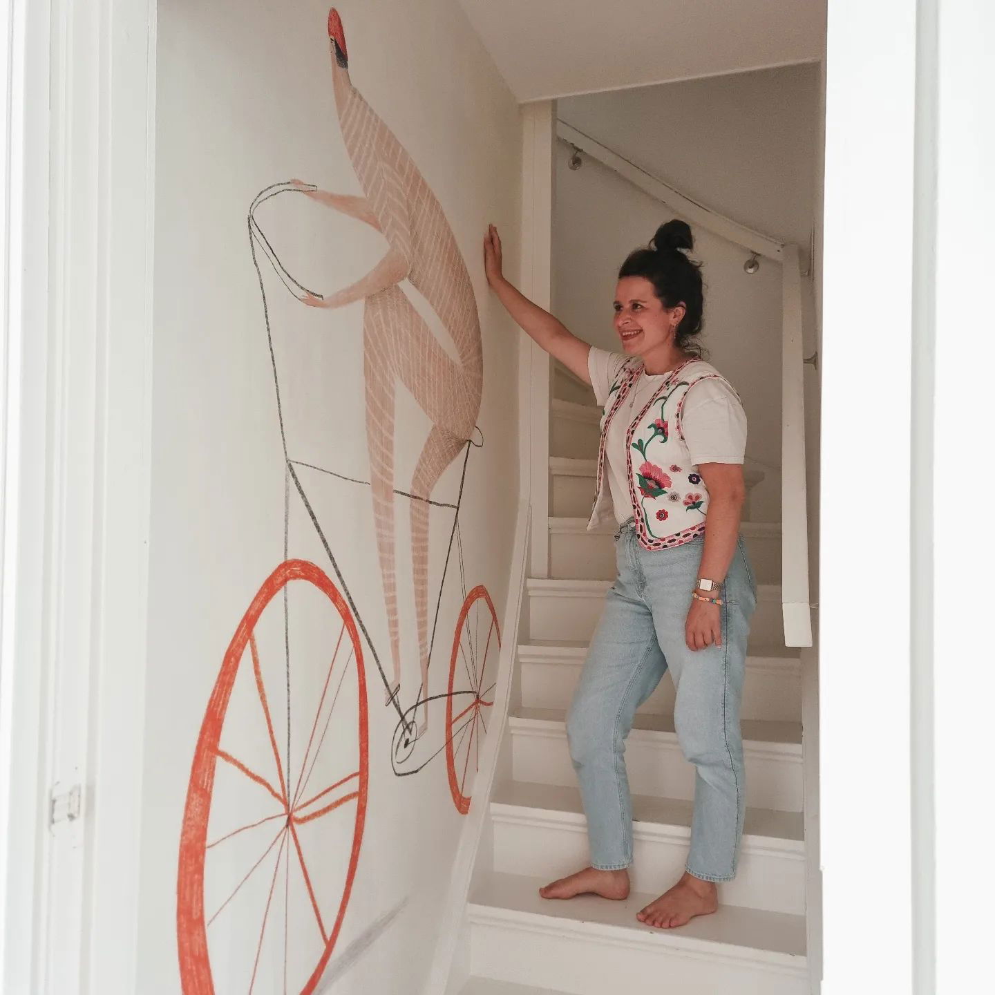 Donna sulle scale accanto a un'opera d'arte murale di una persona che va in bicicletta.