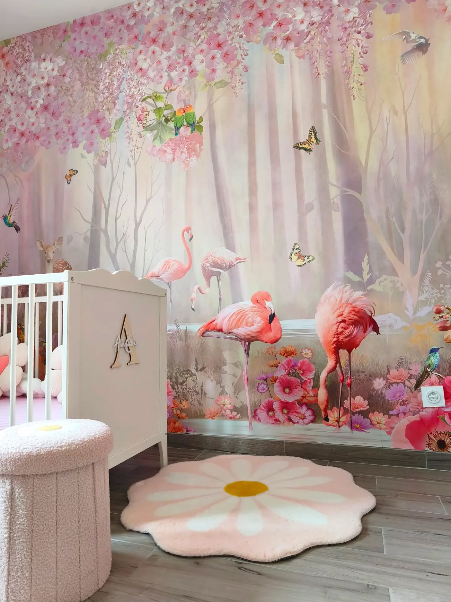 Nursery with flamingo and floral wallpaper, crib, and daisy rug.
