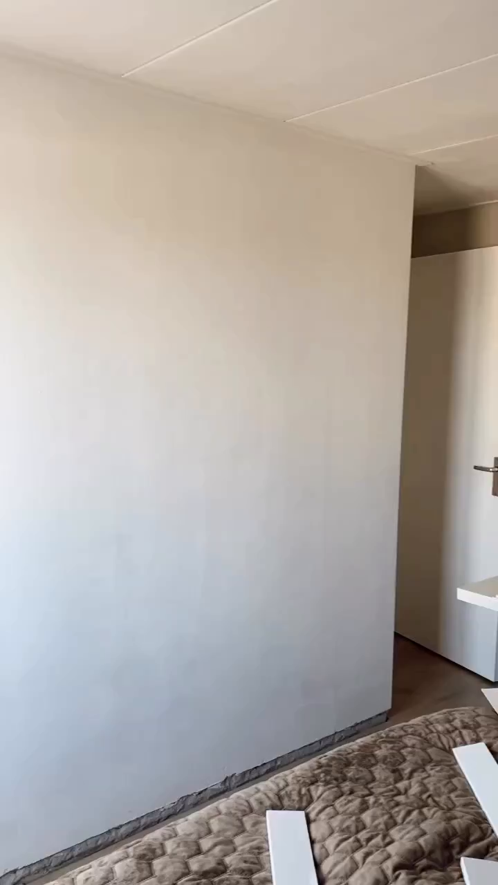 Interior view of a room with a white wall, door, and trim pieces on a brown quilt.