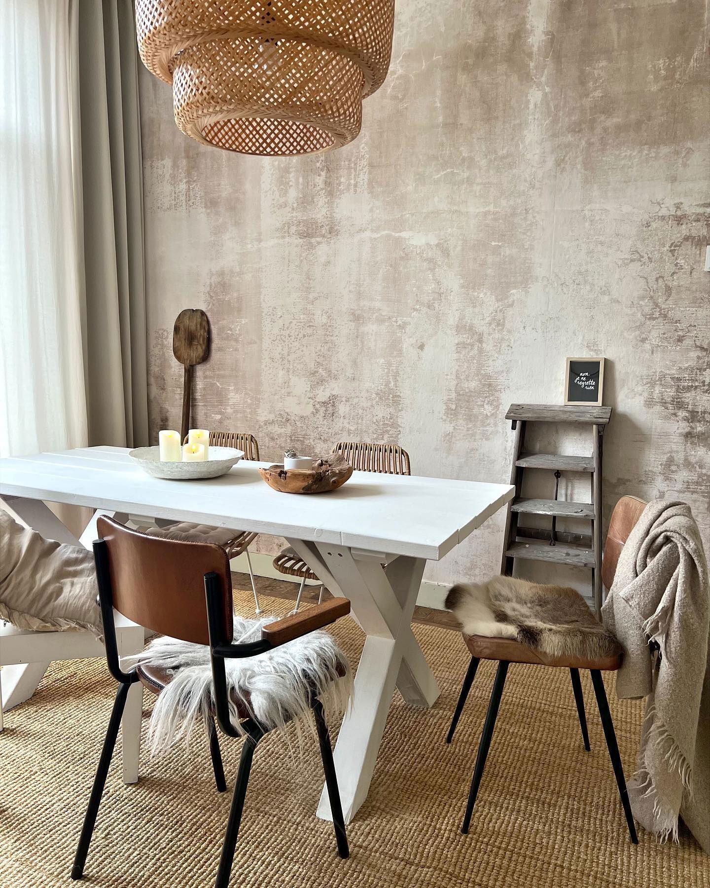 Dining room with white table, leather chairs with fur accents, and woven pendant light.