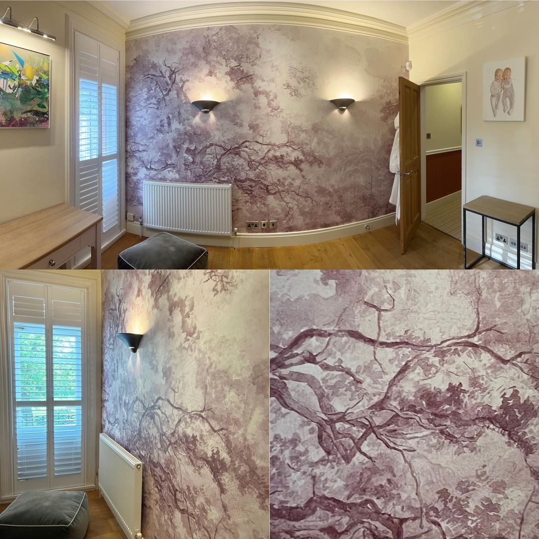 Chambre avec papier peint sur le thème des arbres, éclairage par applique et volets blancs.