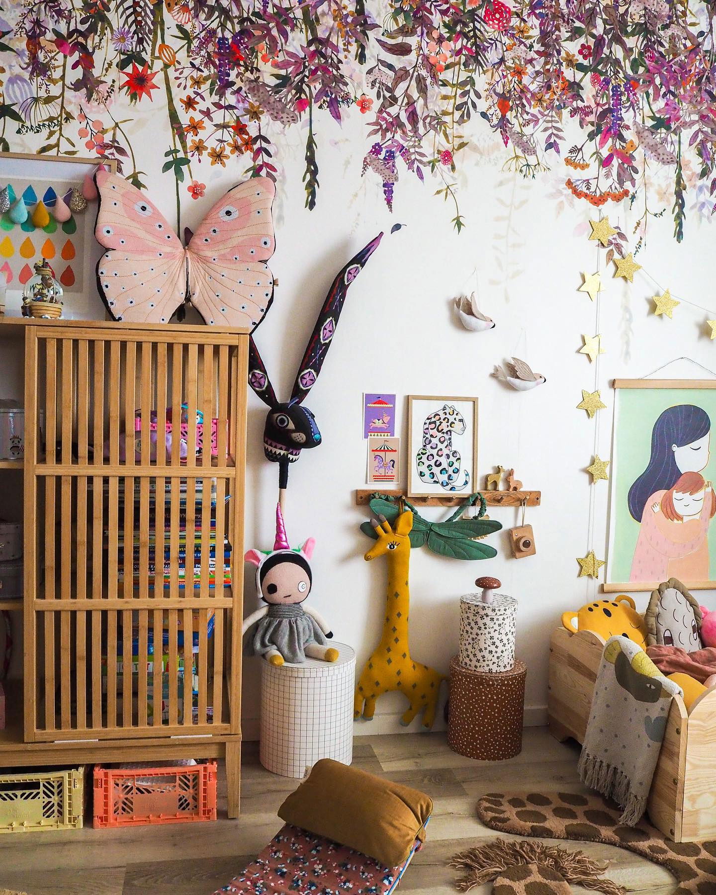 Child's room with floral wallpaper, wooden shelving, and stuffed animal decor.