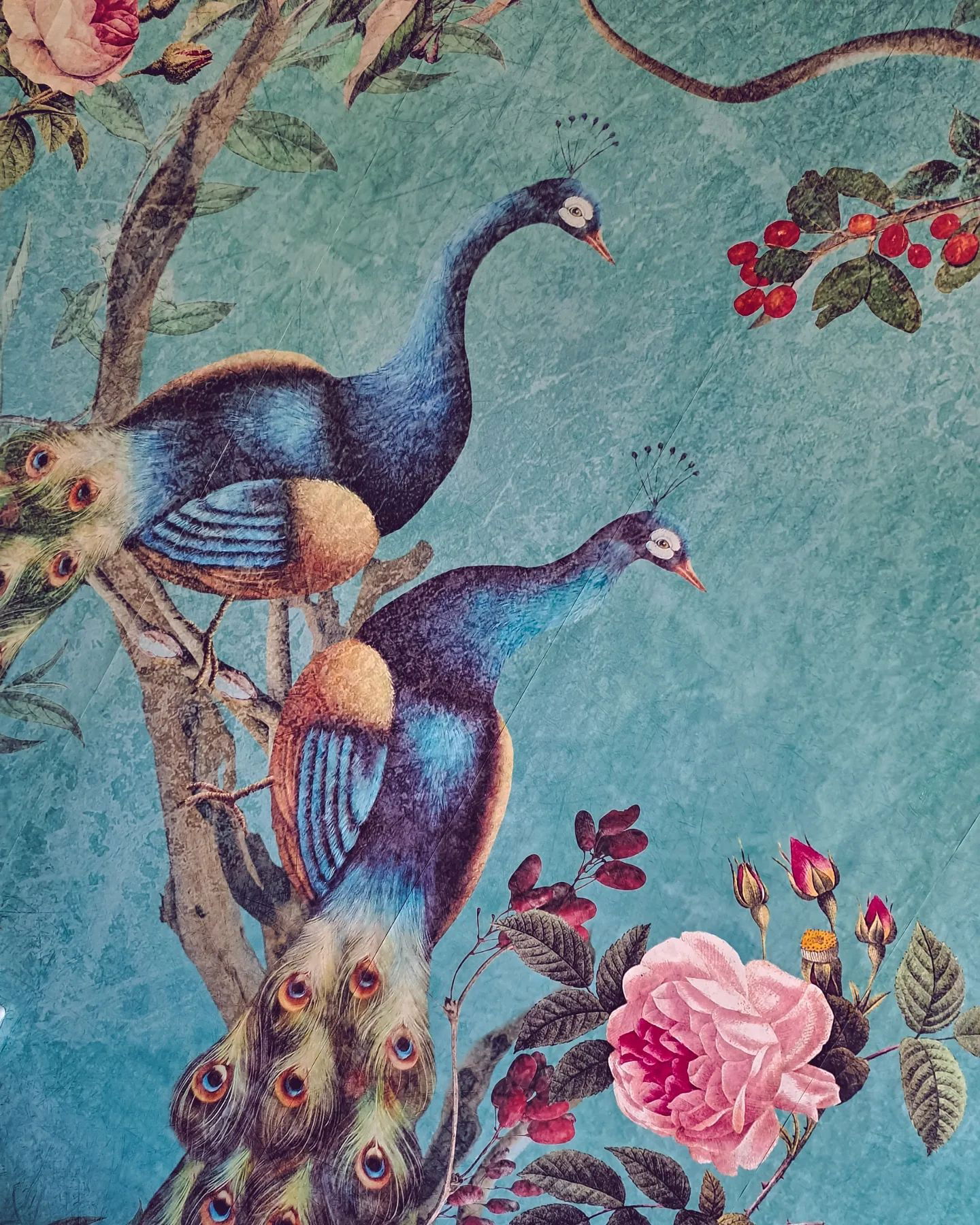 Papier peint de style vintage avec des paons, des roses et des baies sur un fond bleu.