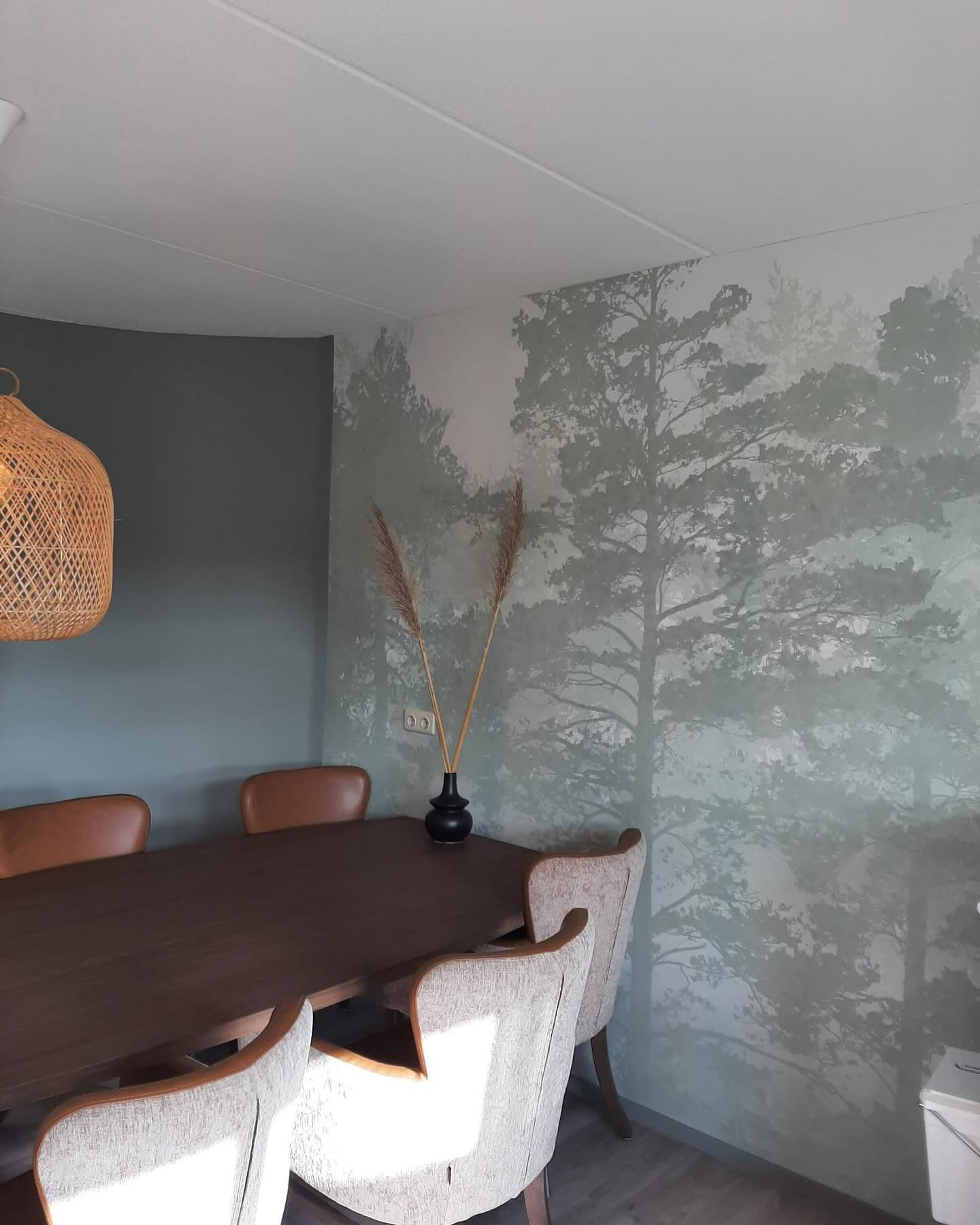 Dining room with wood table, upholstered chairs, and forest mural wall.