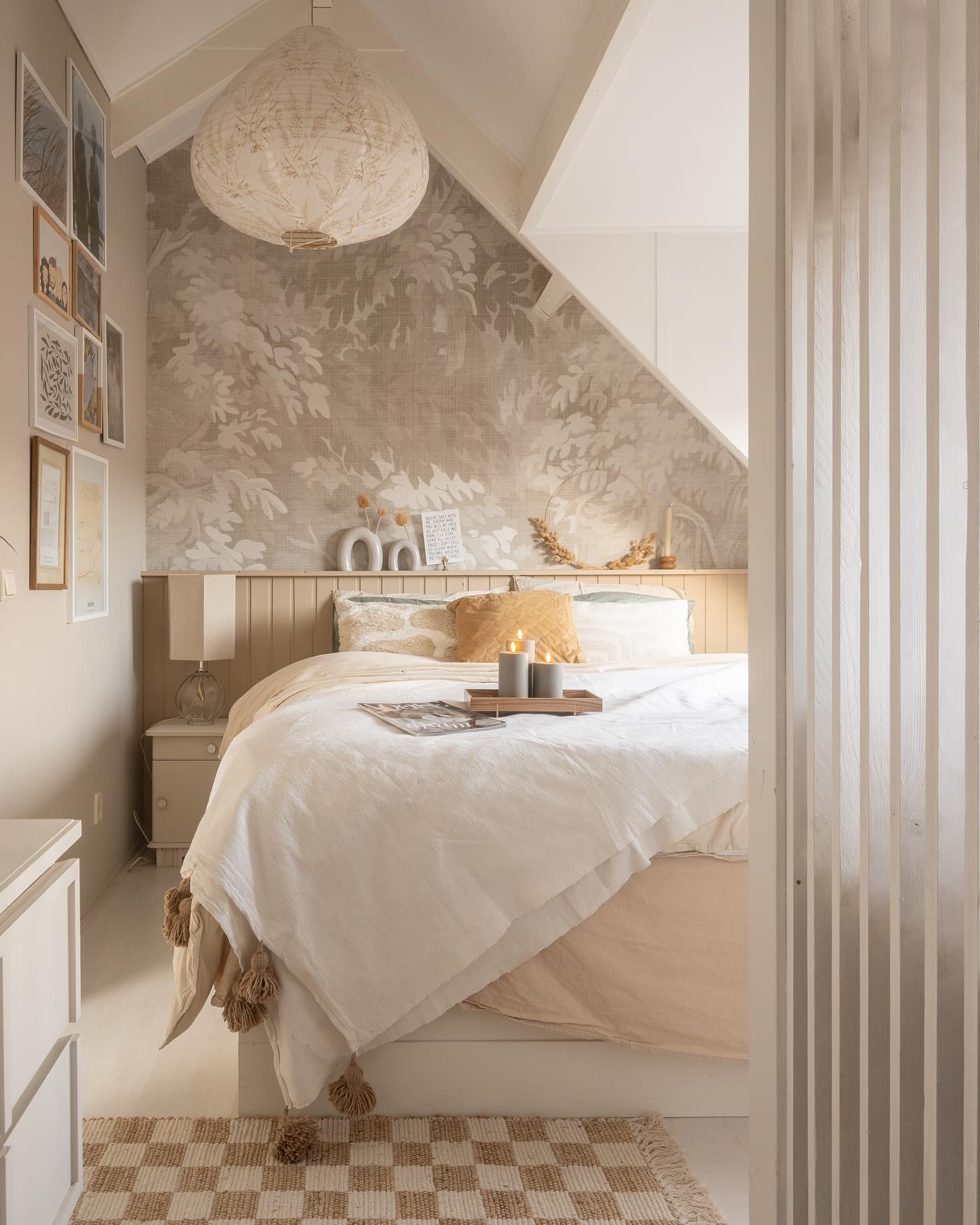 Cozy bedroom with white bedding, tan accents, and a leaf-patterned accent wall.