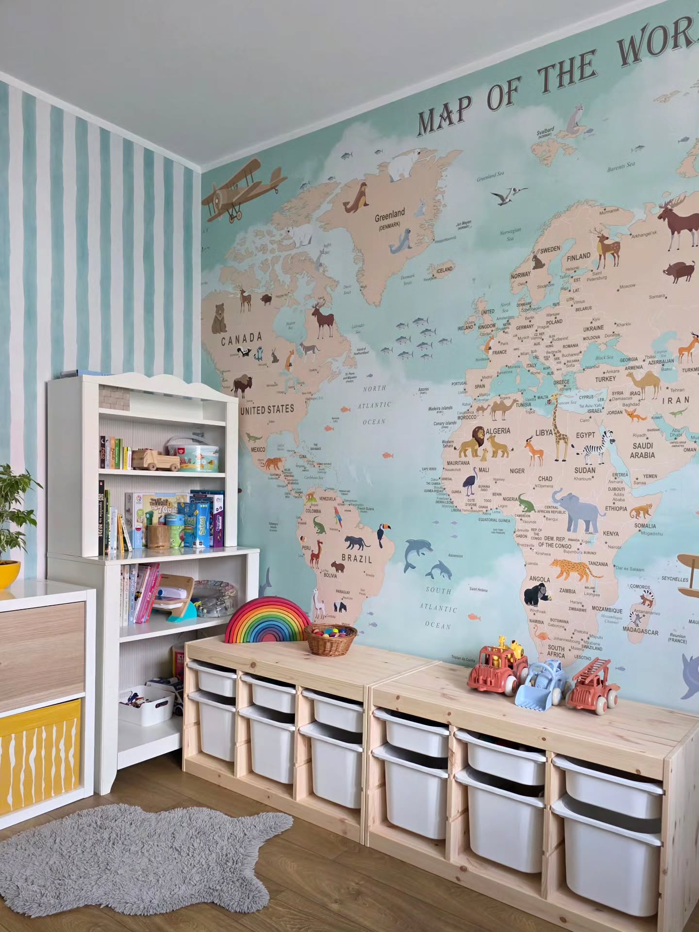 Child's room with world map wallpaper, white shelving, and storage bins.