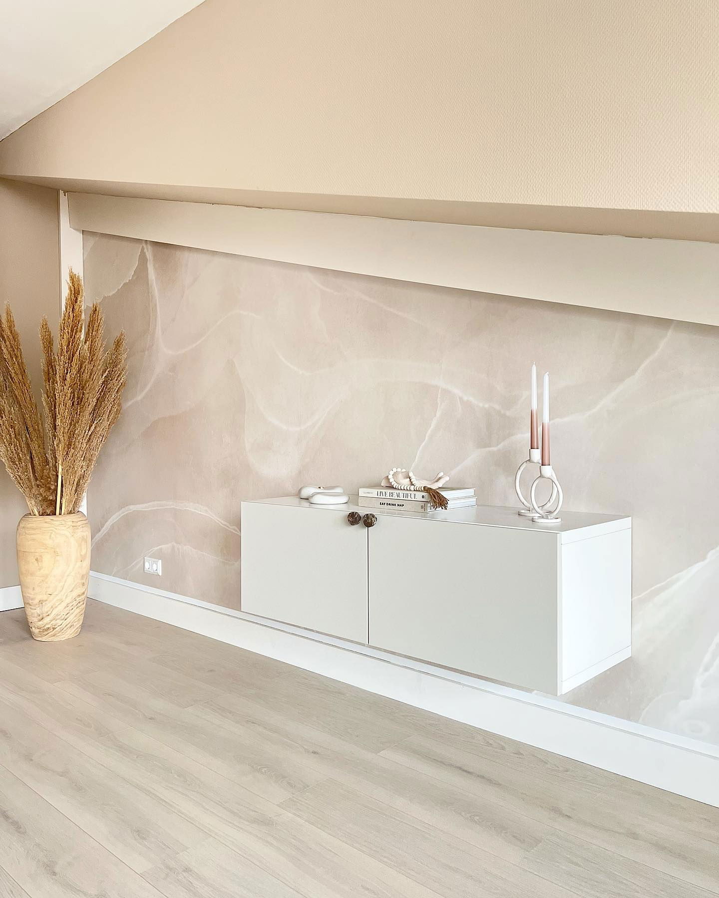 Soggiorno moderno con mobile bianco, parete decorativa in marmo e erba di pampa in un vaso di legno chiaro.