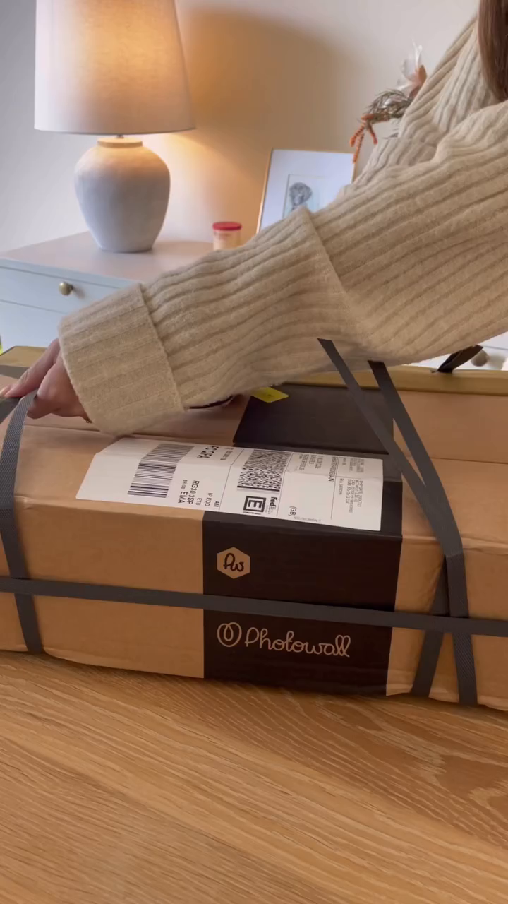 A Photowall package with gray straps sits on a wooden table.