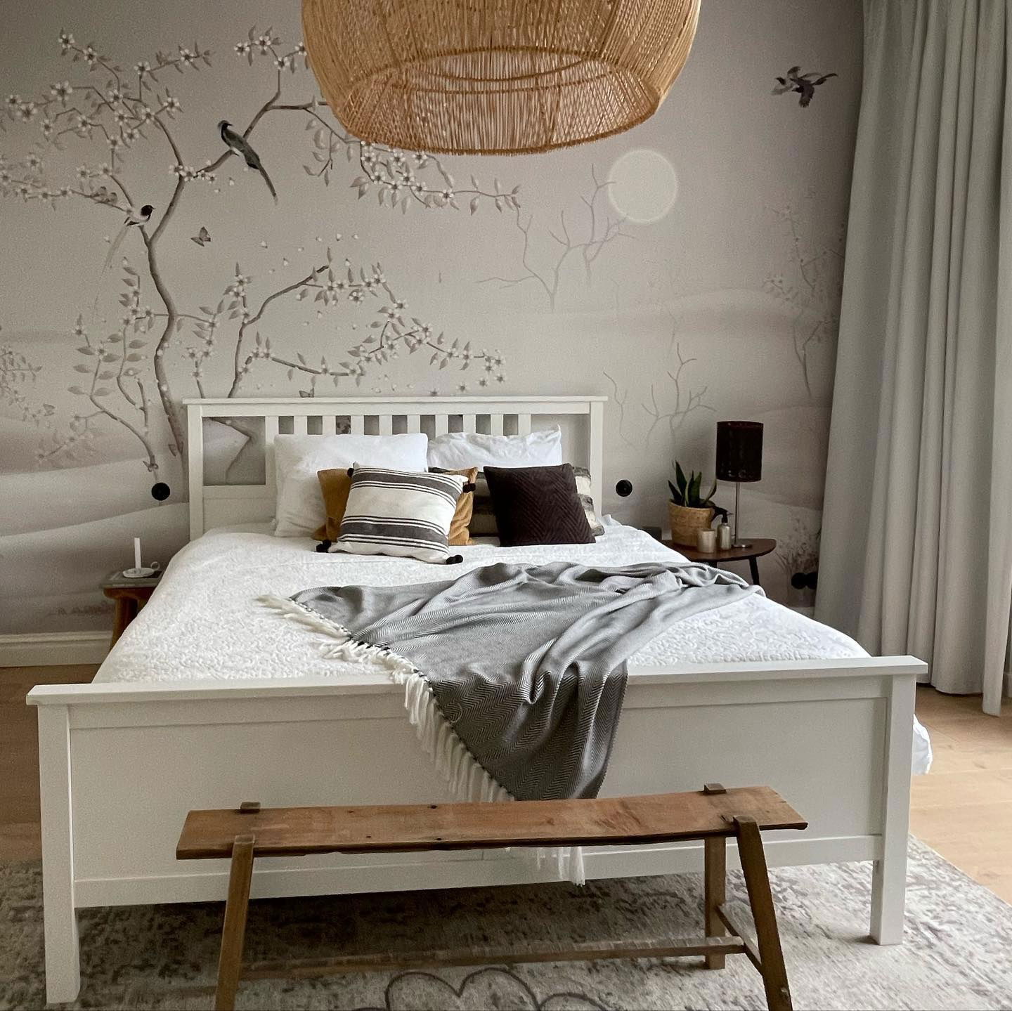 Chambre avec lit blanc, papier peint à motifs et suspension tissée.