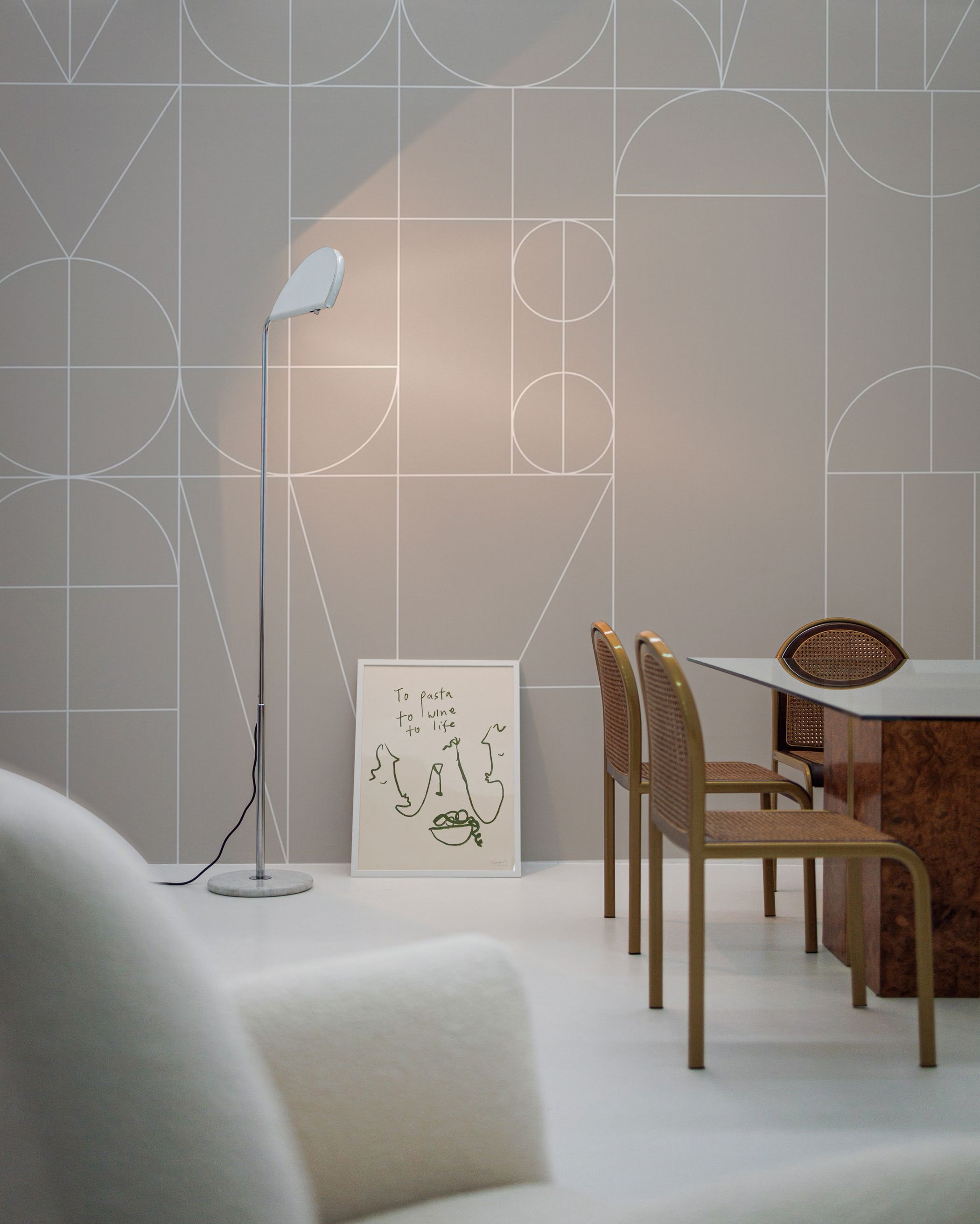 Minimalist interior featuring geometric wallpaper, standing lamp, framed art, and dining set.