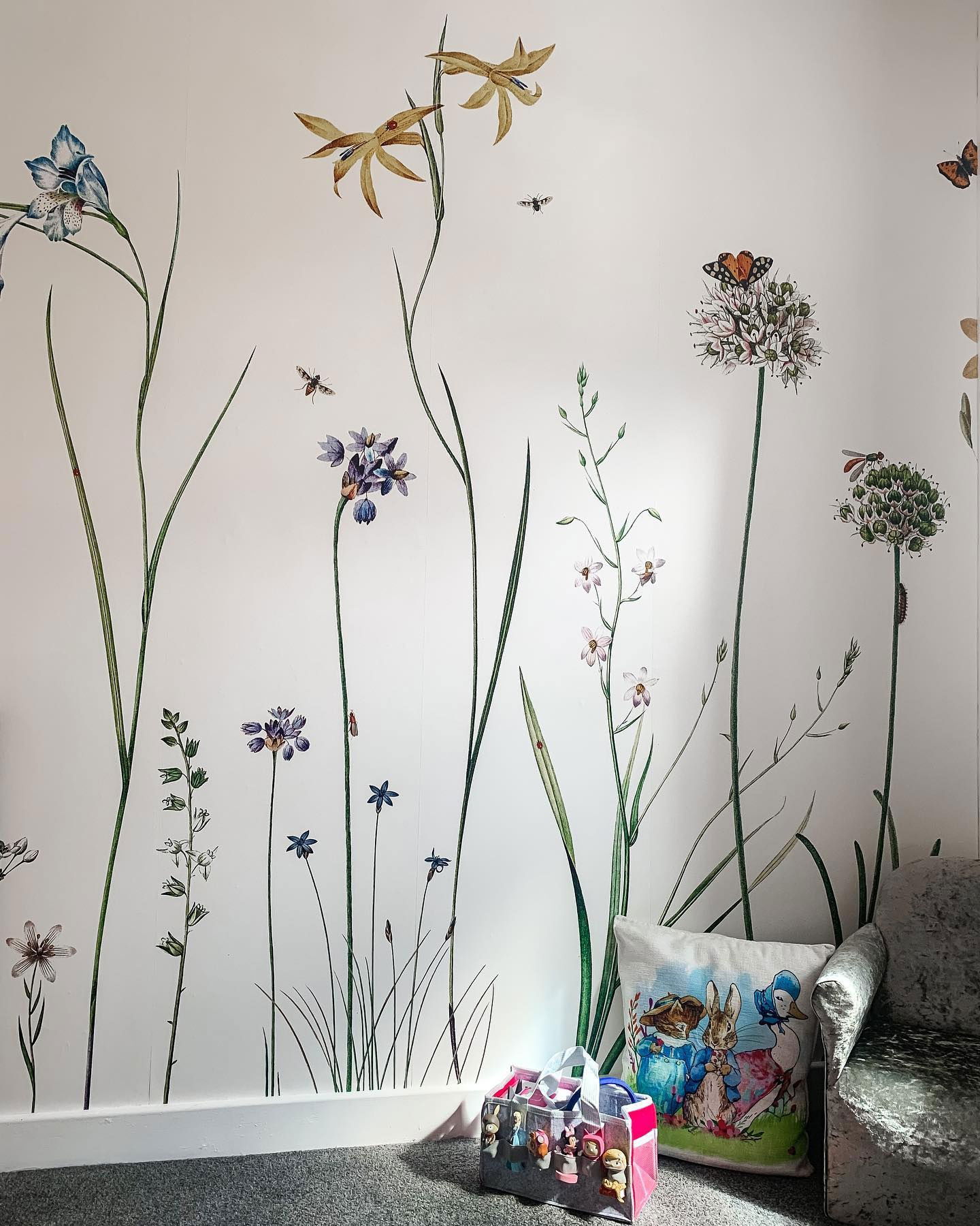 Intérieur avec papier peint floral, oreiller Pierre Lapin et sac de jouets.