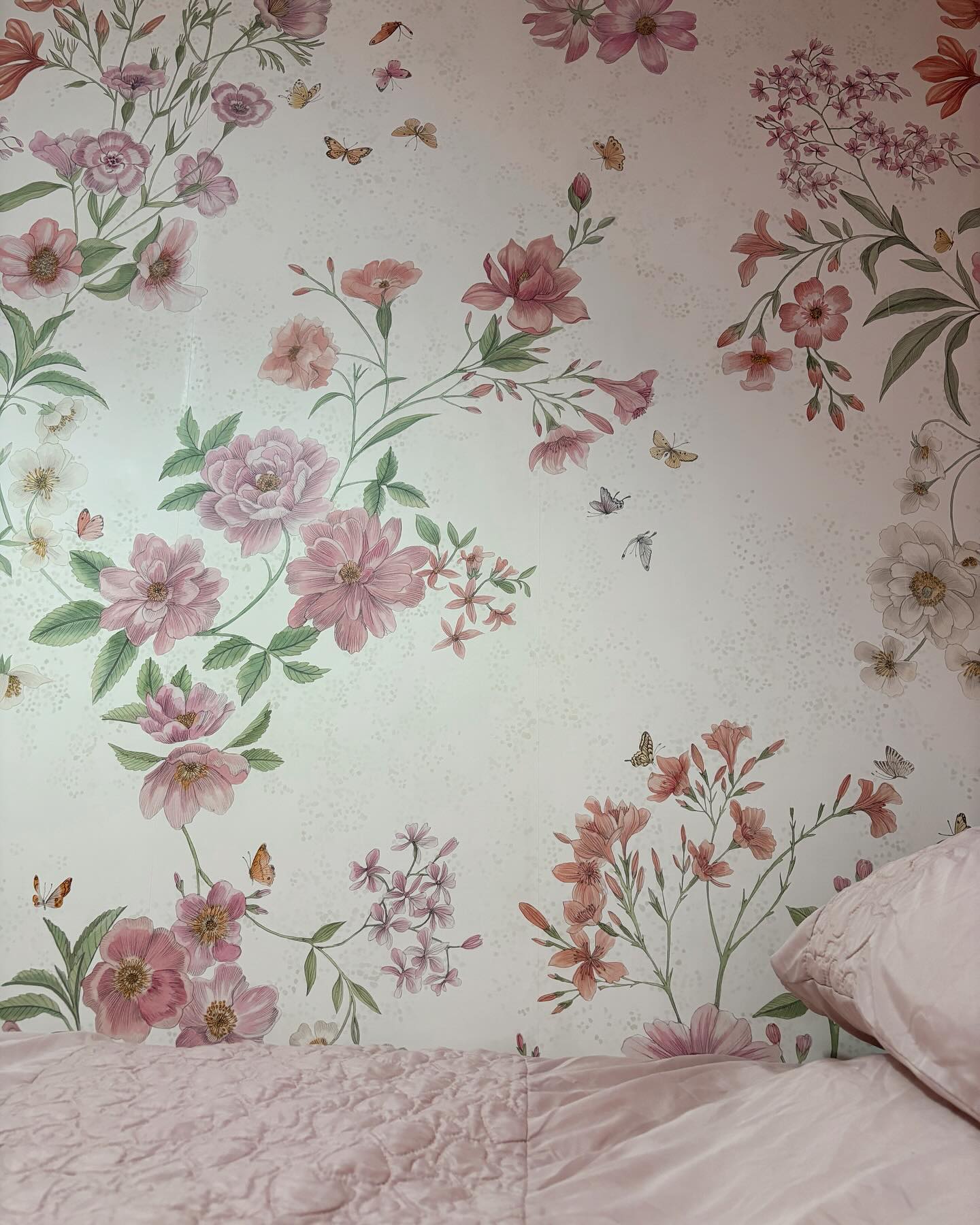 Blommig tapet med rosa sängkläder.